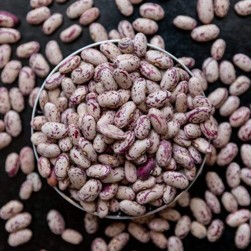 Cranberry roman beans in a bowl and around on a dark background. top view.